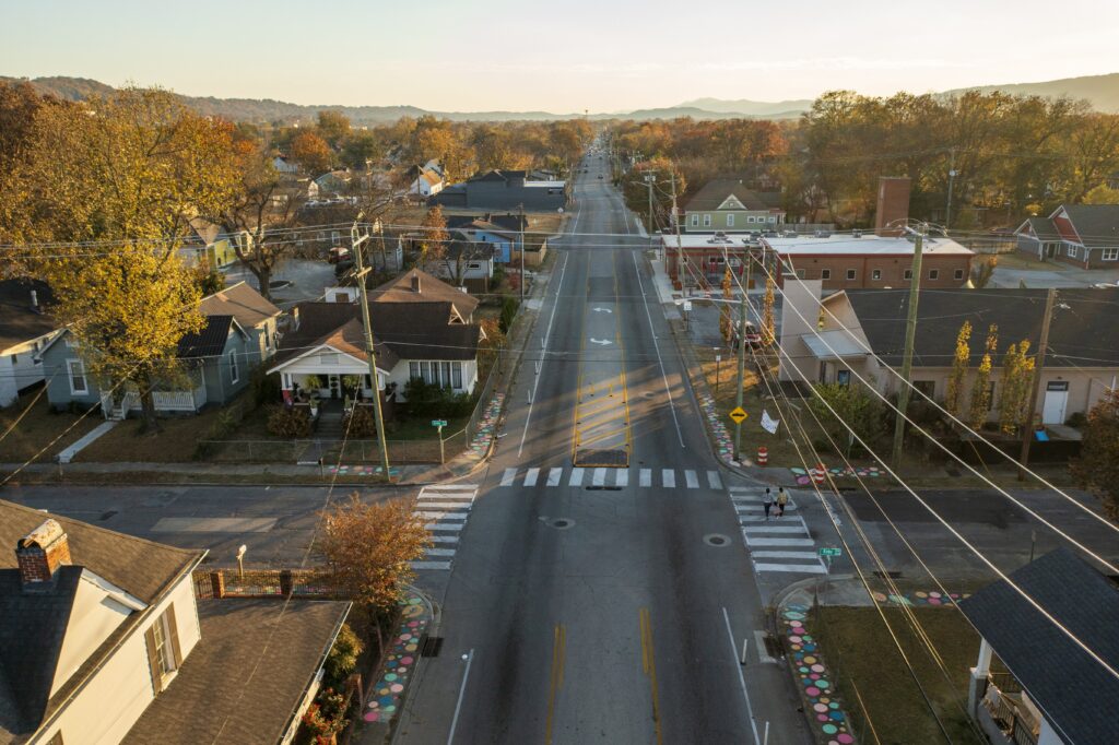 Overhead photo of a three-lane street in Chattanooga, TN, where a quick build demonstration project has resulted in additional crosswalks, activated sidewalks, and bollard-protected bike lanes