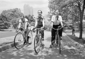 Three cyclists travel down a wide path in this black-and-white photo