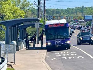 Passengers in a shaded bus stop board the bus in Nashville, which is driving in a designated lane